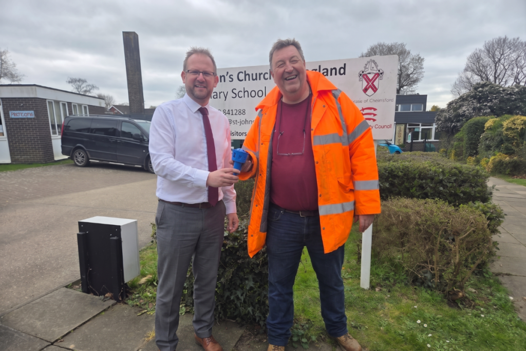 PaveVent™ founder Steve Bays holding the children's water toy that inspired the pothole relief device, shaking hands with a headmaster outside a local school.